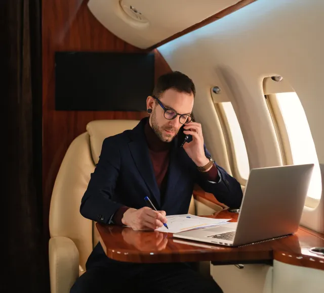 Connectivity for business aviation and private jets A private jet passenger uses their laptop and phone on board.