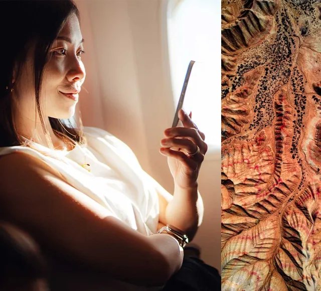 Lady sitting on plane near window using phone for inflight connectivity during flight over mountainous desert terrain