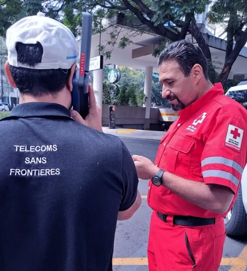 A humanitarian worker from the Red Cross speaks with a telecommunications technician outdoors