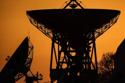 Silhouette d'une antenne satellite contre un ciel orange au téléport de Paris-Rambouillet d'Eutelsat
