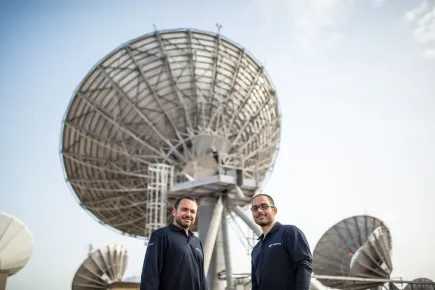 Miembros del equipo frente a una antena satelital en el telepuerto Eutelsat Skylogic Mediterraneo en Cagliari (Cerdeña)