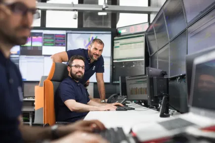 Miembros del equipo con pantallas envolventes en el telepuerto Skylogic, ubicado en Turín