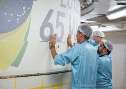 Le logo de la mission EUTELSAT 65 West A étant placé sur le dispositif de protection de la charge utile de l'Ariane 5 par les membres de l'équipe de lancement travaillant à l'intérieur du bâtiment d'assemblage final au Centre spatial (Kourou, Guyane française)