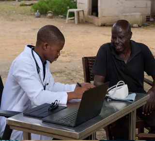 Outdoor medical consultation using a laptop.