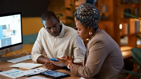 IMAGE_Press_Woman-with-man-at-desk-with-phone_GettyImages-2163189348-121125.webp