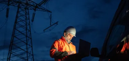 Photo of an engineer working on his laptop during the night on an industrial site