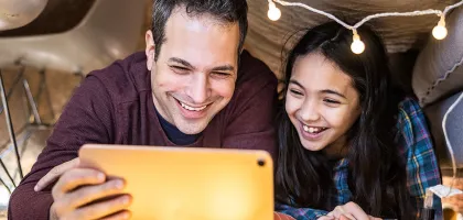 Foto de un padre y una hija viendo una tableta