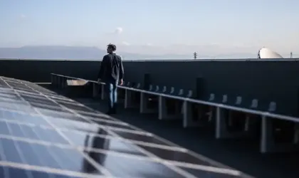 Image of a man walking among solar panels in location Image of a man walking among solar panels in location